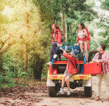 Happy asian young travellers with 4WD drive car off road in forest, young couple looking for directions on the map and another two are enjoying on 4WD drive car. Young mixed race Asian woman and man.